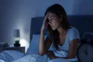 Mujer despierta en la cama por la noche con preocupación y dificultad para dormir por ansiedad nocturna
