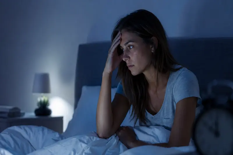 Mujer despierta en la cama por la noche con preocupación y dificultad para dormir por ansiedad nocturna